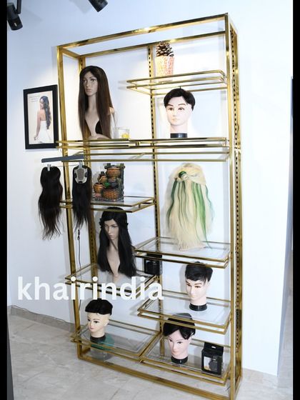 Our new display shelf at the studio, showcasing a variety of wigs, toppers, and colorful extensions. We invite you to come in and explore all the possibilities.