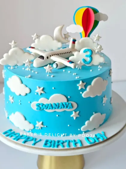 Fasten your seatbelts! This third birthday cake features an airplane flying through a sky of fluffy clouds and stars, with a colorful hot air balloon topper.