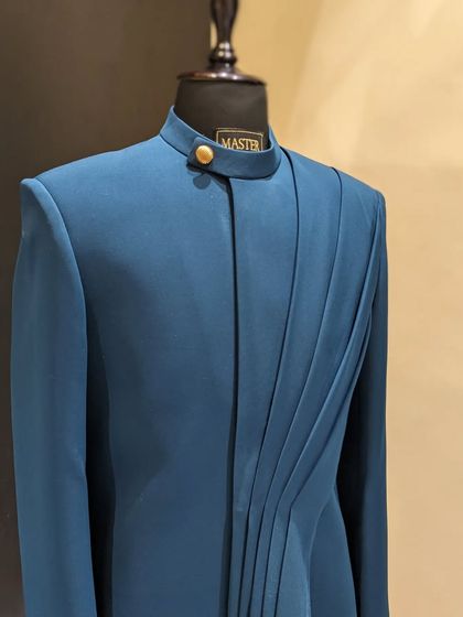 This teal blue Indo-Western jacket features unique pleated detailing on one side, offering a subtle yet distinctive twist on a classic silhouette.