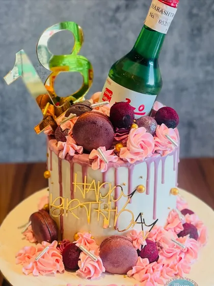A trendy cake for an 18th birthday. This design features a drip effect, macarons, and a miniature bottle of Soju, making it a fun and modern way to celebrate becoming an adult.
