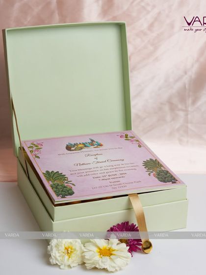 A pastel green invitation box designed for a thread ceremony. The box opens to reveal a lovely pink illustrated card, creating a soft and elegant unboxing experience for this special occasion.