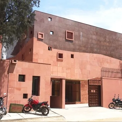 The main facade of the Karigar Centre for Titan Jewellery in Hosur. This project showcases our commitment to using honest, contextual materials. The entire facade is clad in red sandstone, with asymmetrically placed windows that create a unique and sculptural presence, designed to inspire the artisans working within.