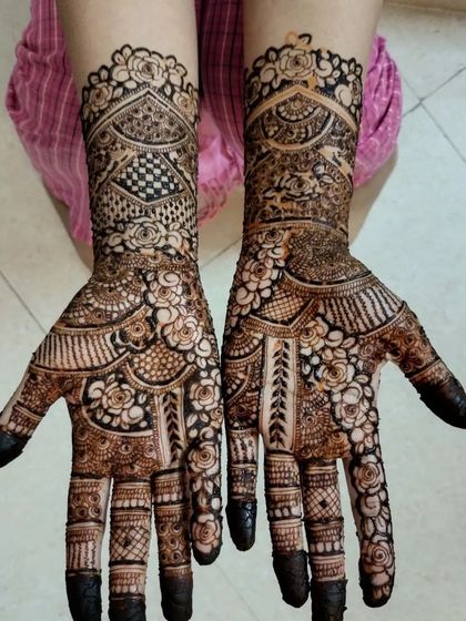 A closer look at the intricate engagement henna. The design is packed with detail, including florals, checkerboard fills, and delicate lines on the fingers.