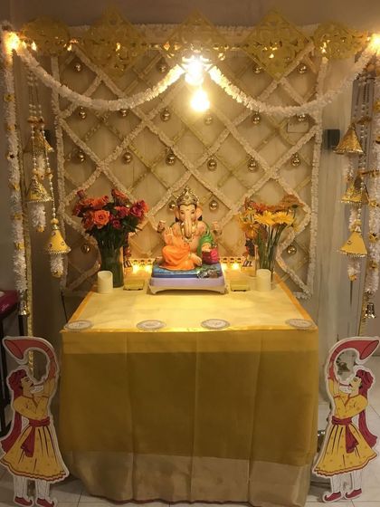 A traditional yellow and white themed mandap with a lattice backdrop and hanging bells. The small cutouts of guards add a unique, classic touch.