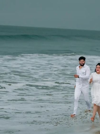 A wide shot of a couple enjoying a walk on the beach, capturing the vastness of the ocean. This kind of environmental portrait is perfect for adventurous couples.