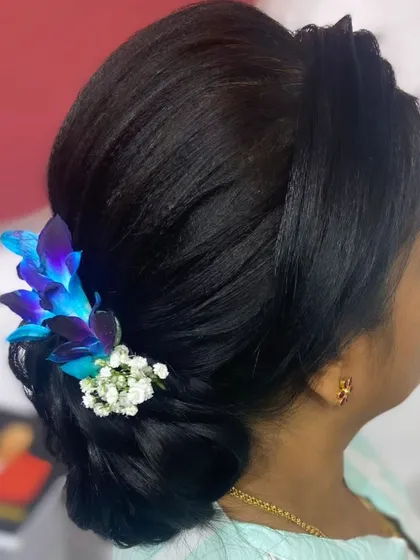 A classic low bun adorned with beautiful fresh blue orchids. This is a sophisticated and elegant hairstyle for any formal occasion.