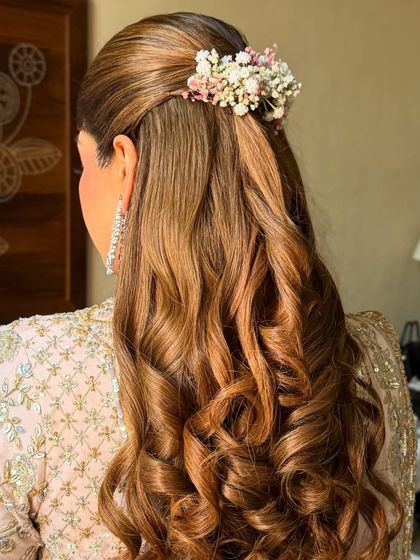 A side view of the floral half-up style, showing the soft texture of the curls and the delicate flower placement.