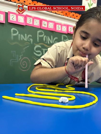A young camper carefully blows a ping pong ball through a winding path. This 'Ping Pong Play Dough Straw Maze' activity is designed to improve breath control and focus in our pre-primary students.