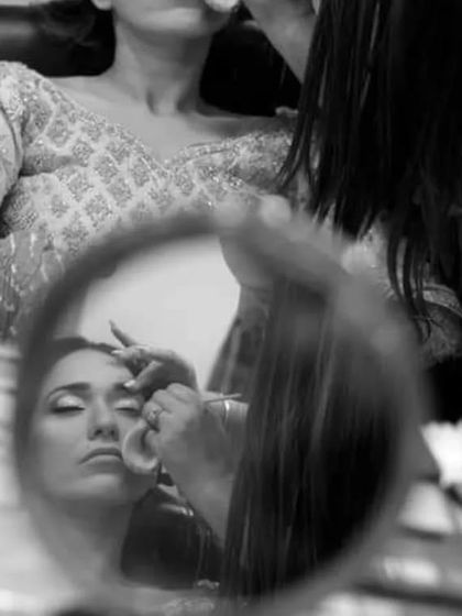 An artistic black and white shot of the bride getting her makeup done, captured through the reflection in a small mirror. This creative perspective offers a unique glimpse into the getting-ready process.