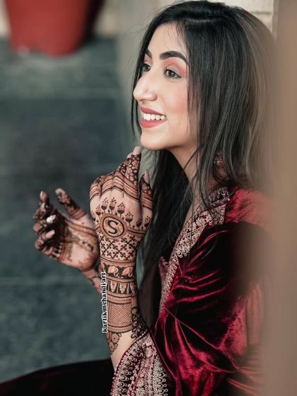 A simple yet elegant way to personalize your mehandi is with a beautifully designed initial, like the letter 'S' featured prominently on the back of the hand.