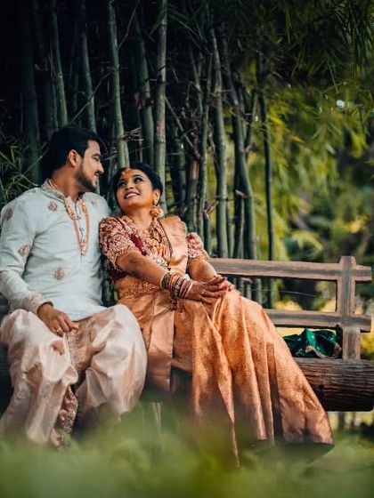 A serene moment shared by a couple on a wooden bench surrounded by bamboo, a peaceful escape during their wedding day.