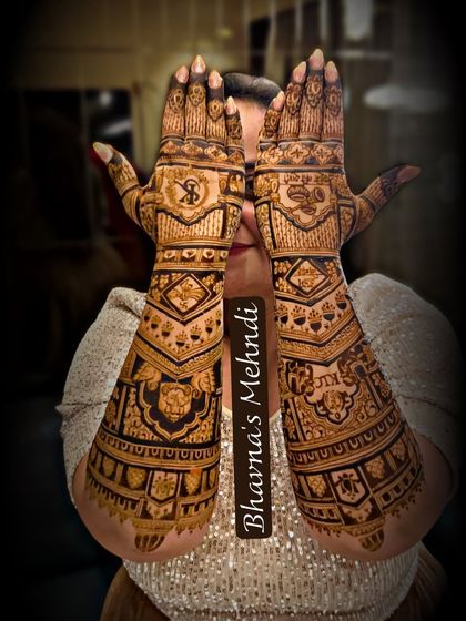 A bride peeking through her beautifully adorned hands. This full-arm bridal mehndi is a masterpiece of patterns and symmetry.