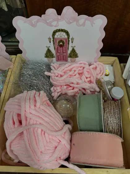 A tray of craft supplies, including soft yarn, ribbons, and glitter, for the Christmas ornament decorating activity.