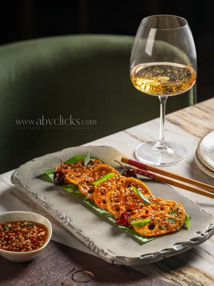Crispy lotus stem appetizer, elegantly plated and paired with white wine at Camo, Noida.