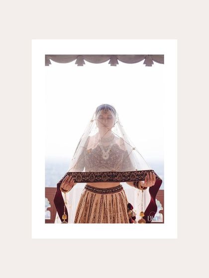 A minimalist portrait of a bride holding her veil, framed in white.