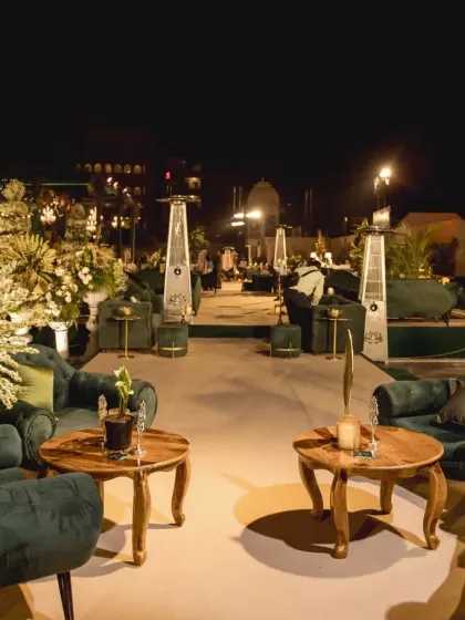 An elegant outdoor reception lounge with plush green sofas and warm lighting, creating a sophisticated space for guests to relax and mingle under the stars.
