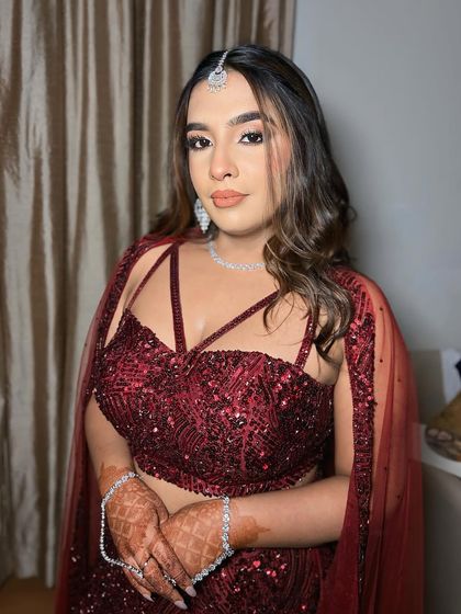 An engagement beauty in a stunning red sequined lehenga. The makeup is glamorous yet soft, with a focus on her eyes and a flawless base.