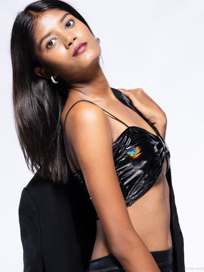 A three-quarter shot of a model in a black vinyl top, with a cool and confident pose.