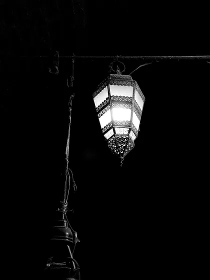 An ornate street lamp illuminates the night in a dark alley. Even after sunset, the lanes of Old Delhi hold a mysterious and captivating charm that we love to explore.