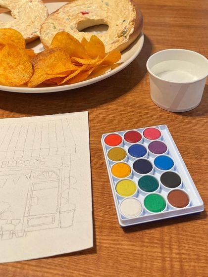 My weekend setup: a bagel, some chips, and a watercolor painting in progress. This behind-the-scenes shot shows the sketch and palette for the flower shop illustration.