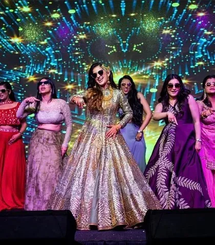 The bride and her tribe looking fierce. Using props like sunglasses can add a fun, modern twist to any sangeet performance.