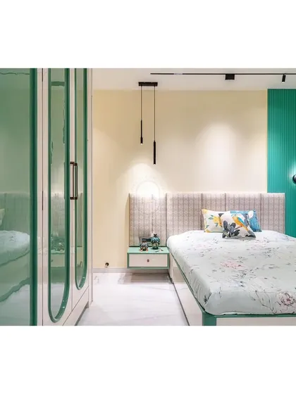 In this view, you can see how the different elements of the bedroom come together. The patterned headboard, minimalist pendant lights, and the bold green fluted wall panel create a space rich in texture and personality, all tied together with a soft, calming color scheme.