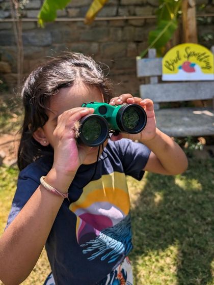 A young birdwatcher, focused and ready for discovery. We provide kid-friendly binoculars to help our little explorers get a closer look at our feathered friends.