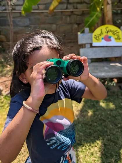 A young birdwatcher, focused and ready for discovery. We provide kid-friendly binoculars to help our little explorers get a closer look at our feathered friends.