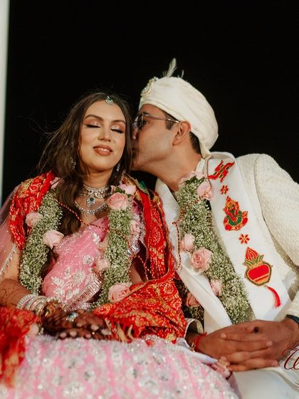 A sweet kiss on the cheek from the groom, a moment of tenderness during the wedding rituals.