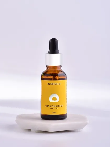 A product-centric shot of Moon Forest's face oil on a marble pedestal. The clean, bright lighting emphasizes the product's purity and quality.