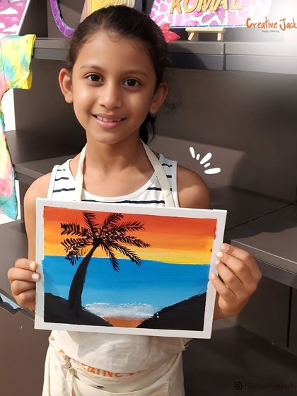A young girl smiles as she holds her painting of a palm tree against a sunset, a beautiful piece she created in one of my kids' art classes.