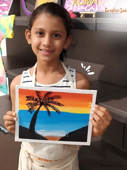 A young girl smiles as she holds her painting of a palm tree against a sunset, a beautiful piece she created in one of my kids' art classes.