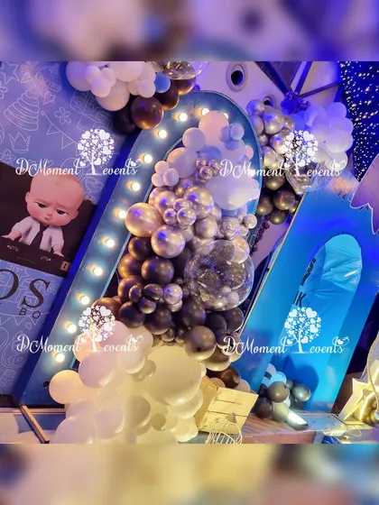 An artistic shot of the "Boss Baby" decor, focusing on the layered backdrops, balloon details, and illuminated elements.