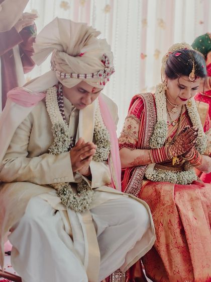The couple during their wedding ceremony, with the bride's dark henna-stained hands folded in prayer.
