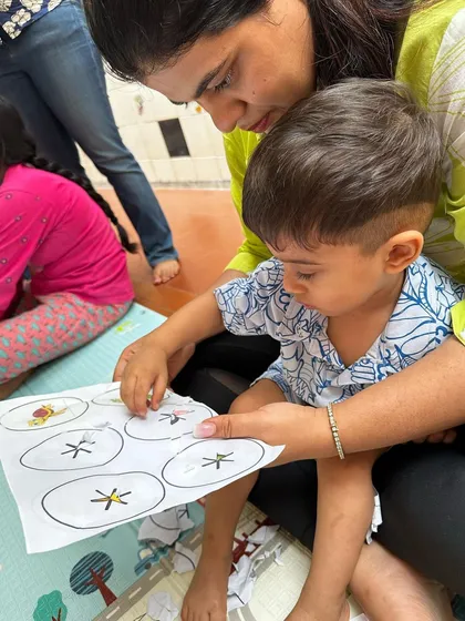 A parent helps their child with a matching activity about baby animals. This one-on-one interaction during our parent-toddler sessions is key for learning and bonding.