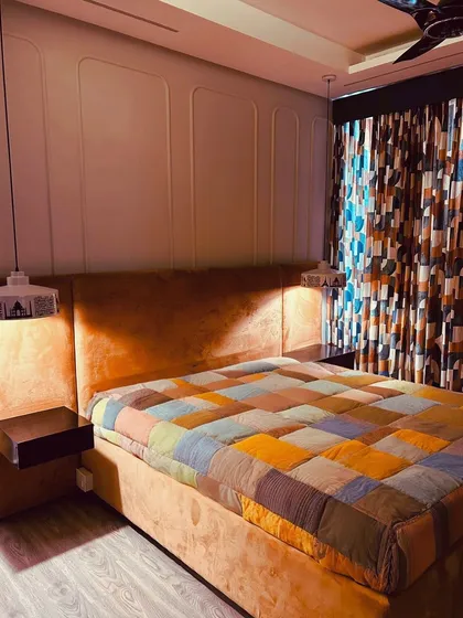 We infused this bedroom with personality and warmth. The custom bed and headboard in a vibrant orange fabric are the focal point, complemented by sleek floating side tables and unique skyline-printed pendant lights. The wall features subtle wainscoting for a classic touch.