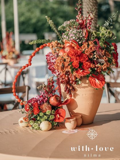 A vibrant centerpiece for a tropical-themed event, featuring a heart shape made of cherry tomatoes, surrounded by an abundance of red flowers and fruits.