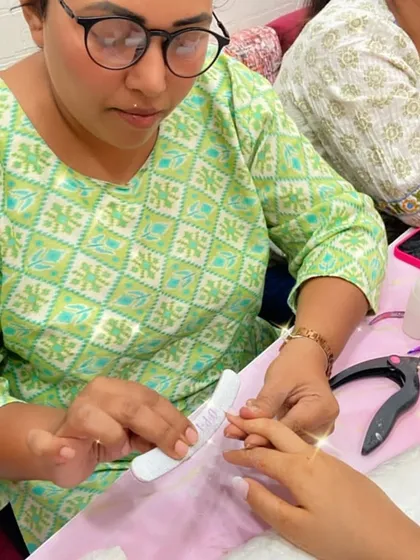 A student carefully files a client's nails, showing the focus required for this foundational step.