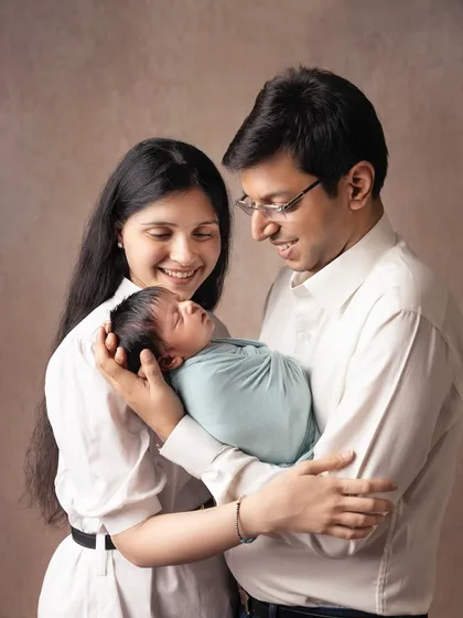 A classic portrait of new parents cradling their sleeping baby. Their gentle smiles and loving gaze towards their child tell a story of pure happiness.