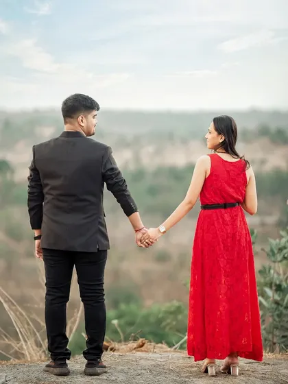 A couple holds hands and looks out over a valley, a powerful and scenic shot from their pre-wedding adventure.