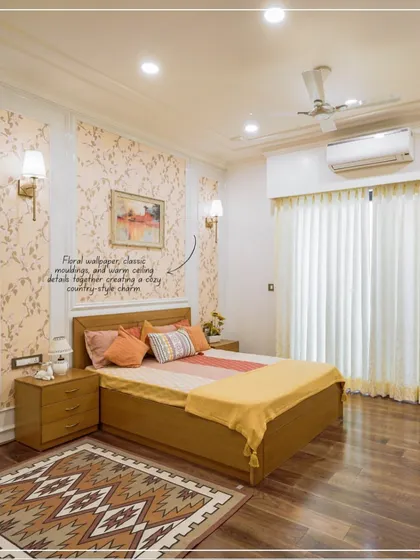 A cozy bedroom with floral wallpaper, classic mouldings, and warm yellow and orange tones.