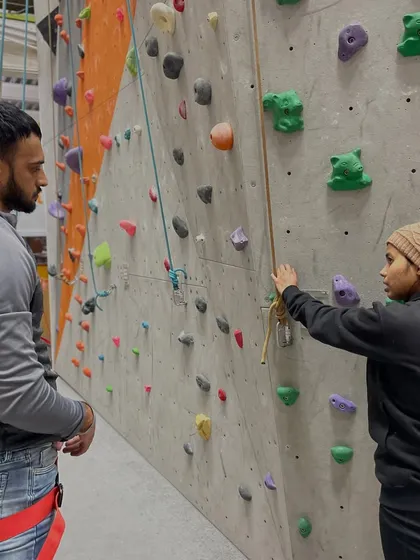 Our staff is here to make sure you understand the basics. In this shot, a duty officer explains the auto-belay system to a new climber, ensuring they feel secure.