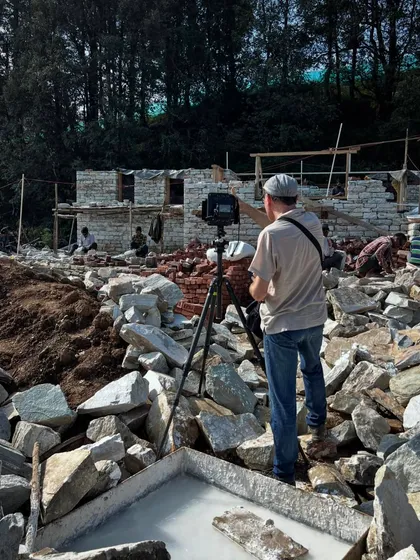 Ariel Huber navigates a field of rubble to capture the perfect shot of the emerging stone walls. Architectural photography is an art that requires a keen eye for composition, even on a chaotic construction site.