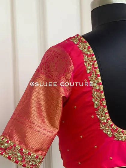 A classic pink blouse with contrasting Kanchipuram silk sleeves. The neckline and sleeve cuffs are embellished with simple yet elegant gold bead and zardozi work.