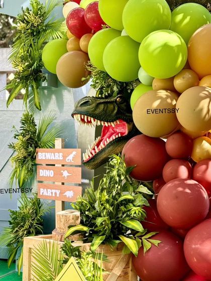 A T-Rex head emerges from a balloon garland, adding a thrilling and dynamic element to the decor.