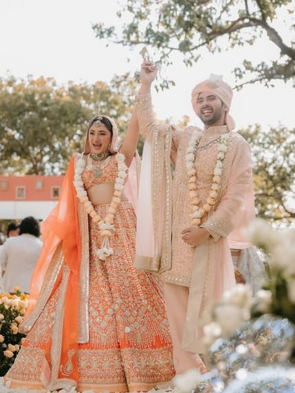A joyous moment from a garden wedding ceremony. The couple stands amidst a sea of white and orange roses, a perfect example of how we use florals to create vibrant, celebratory landscapes.