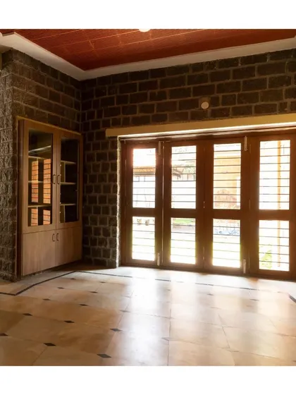 An interior view showing how the ruggedness of the stone wall is balanced by the refined finish of the wooden doors and built-in cabinetry.