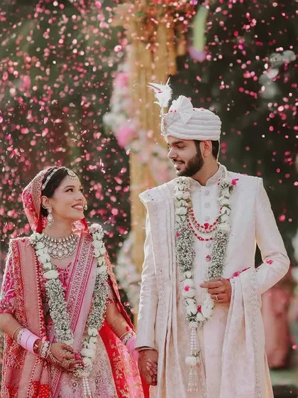 A moment of pure joy as the newlyweds walk hand-in-hand, showered in a cascade of flower petals. We focus on capturing these candid, celebratory moments that define the happiness of your wedding day.