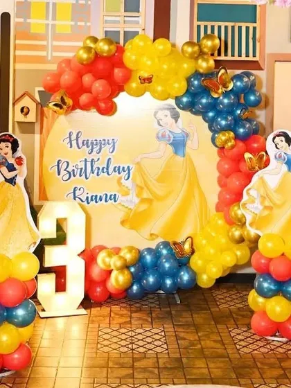 A Snow White themed birthday party for a 3-year-old. This setup includes character cutouts, a marquee number '3', and balloons in Snow White's signature red, yellow, and blue colors.