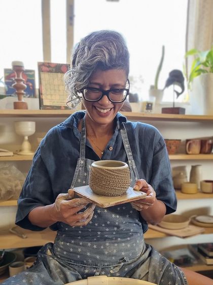 A moment of pure joy at the wheel as I hold up a freshly thrown, textured piece, smiling at the successful creation.